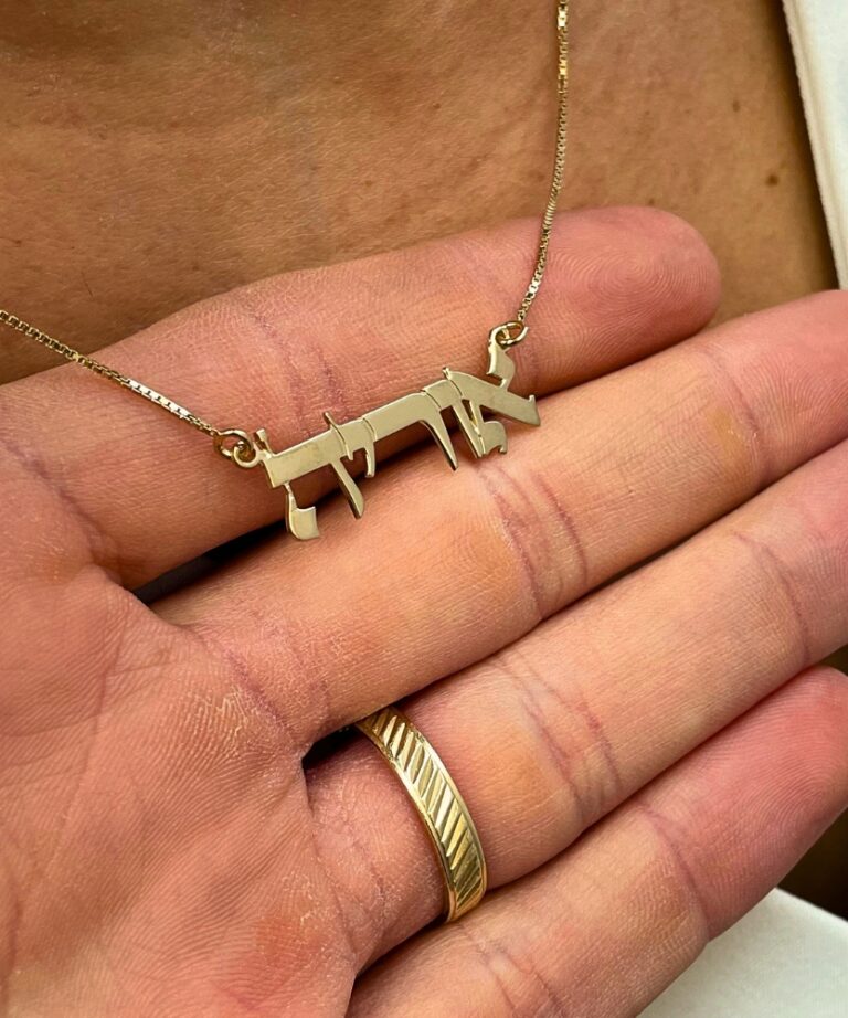 Personalized name pendant shown in close-up hand shot