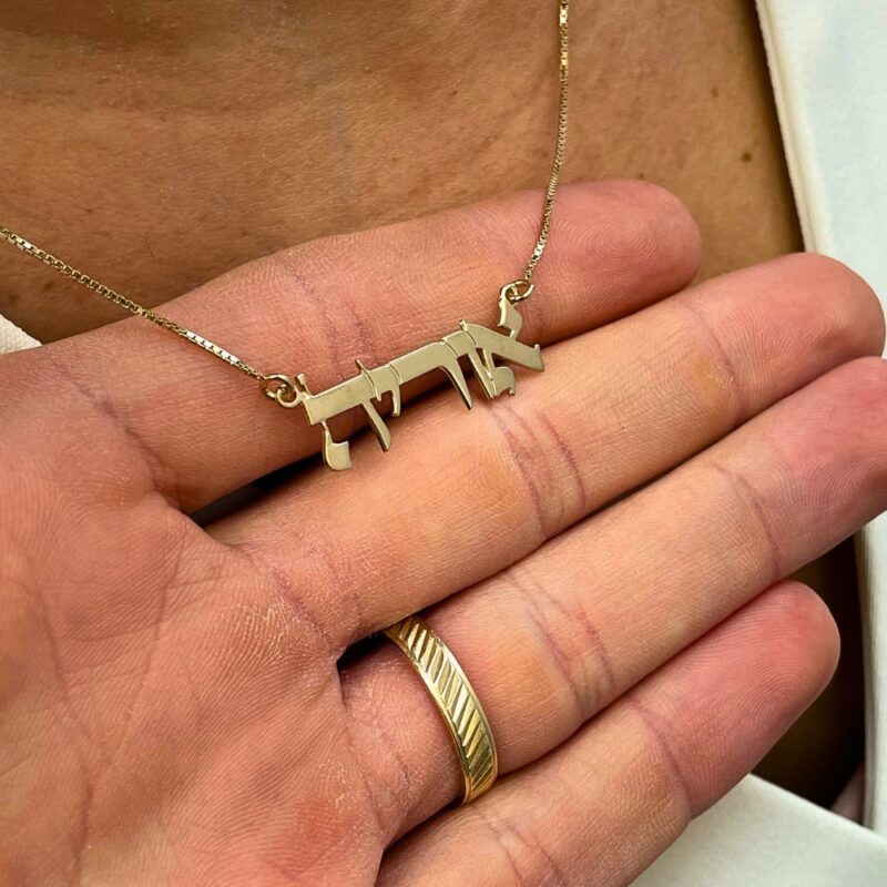 Personalized name pendant shown in close-up hand shot