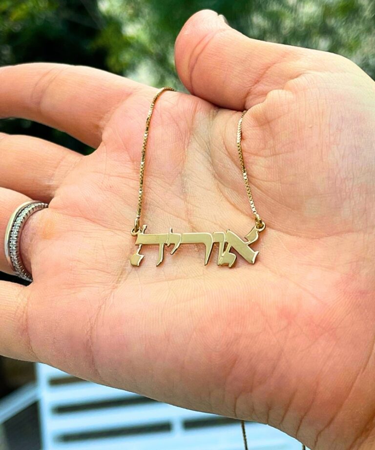 Hand holding a custom-made necklace with blurred green background