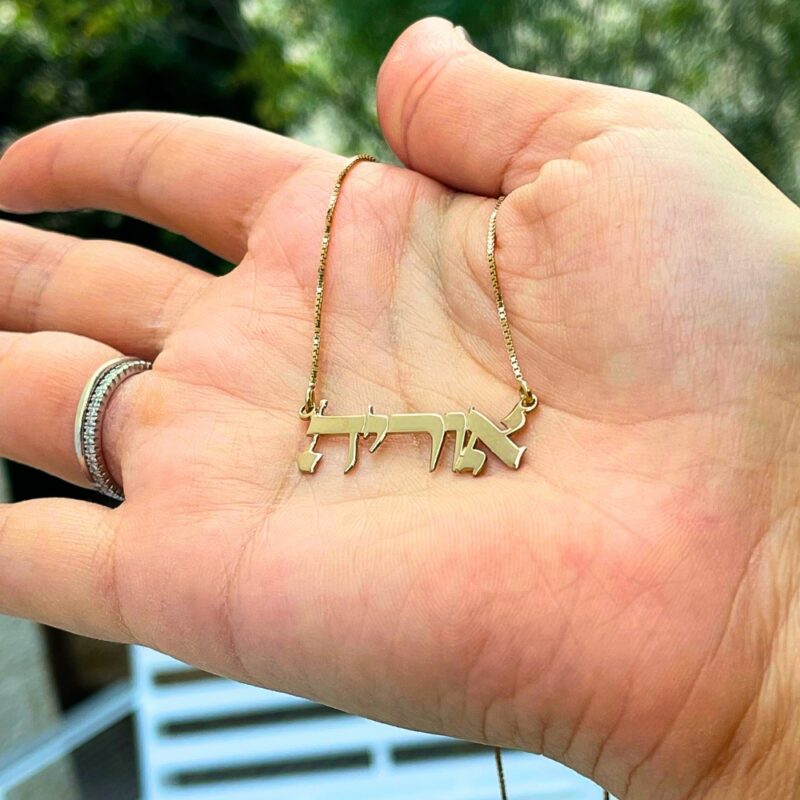 Hand holding a custom-made necklace with blurred green background