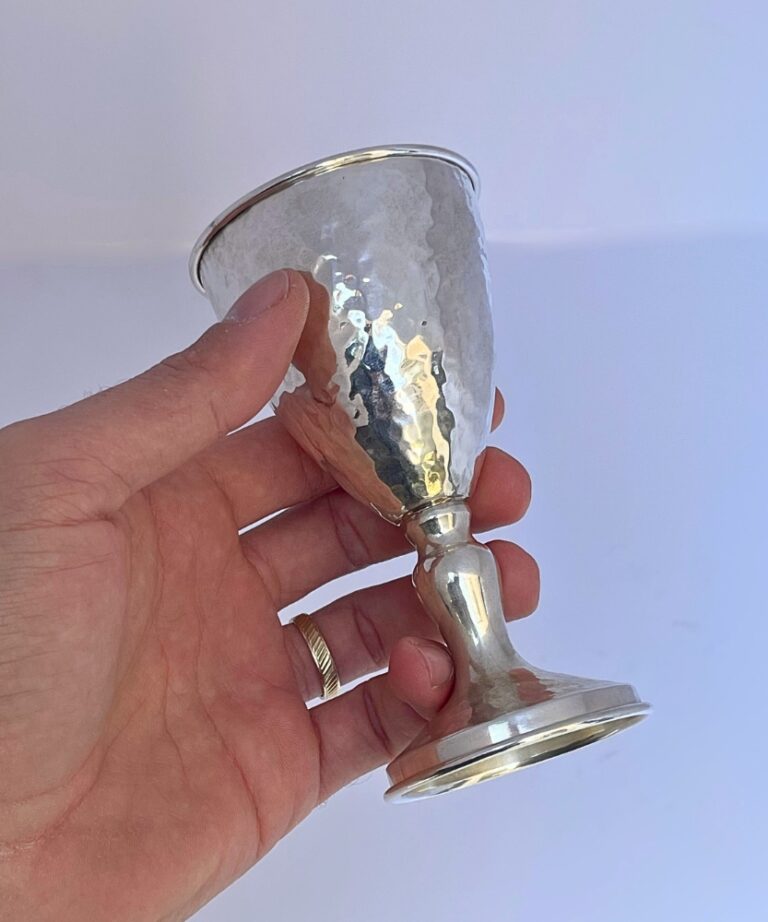 Hand holding a handcrafted Silver Kiddush Cup to show texture and size