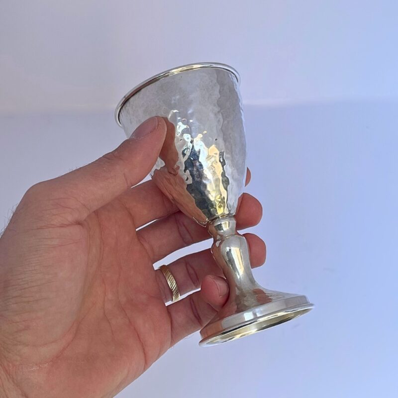 Hand holding a handcrafted Silver Kiddush Cup to show texture and size