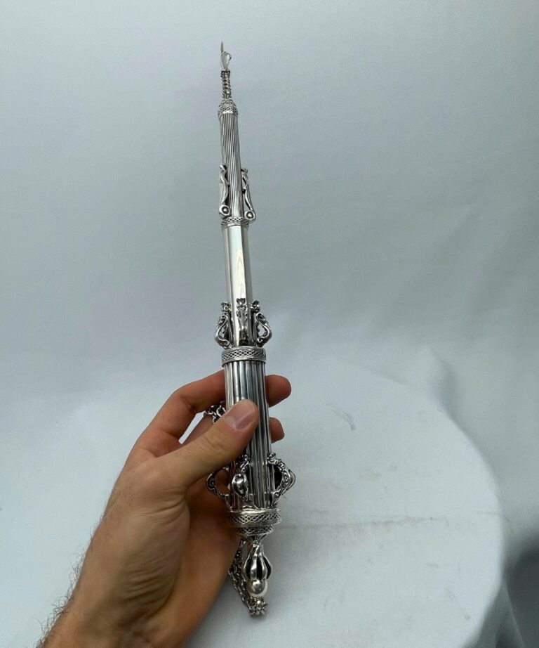 Hand holding a traditional Torah pointer for scale