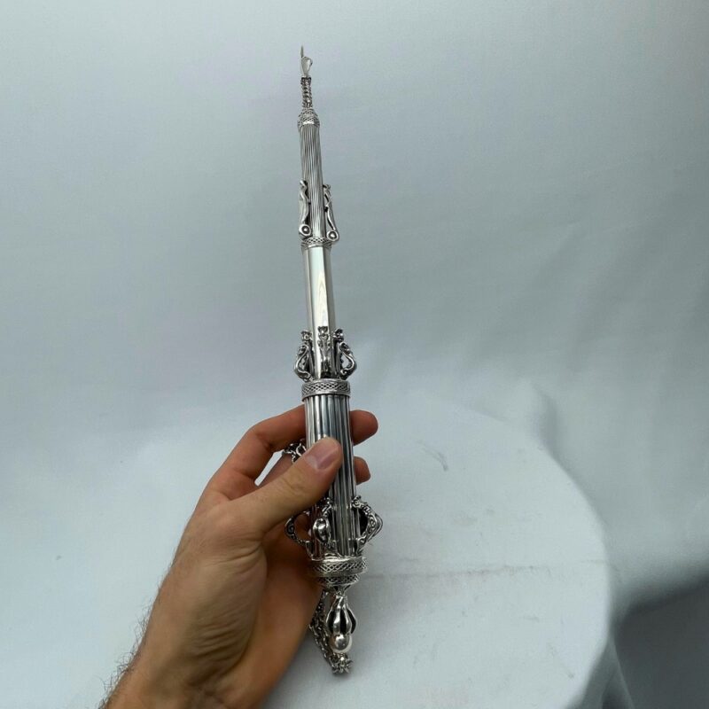 Hand holding a traditional Torah pointer for scale