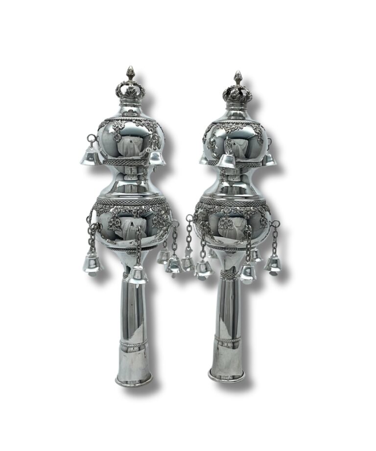 Handcrafted silver Torah finials with intricate decorations and bells