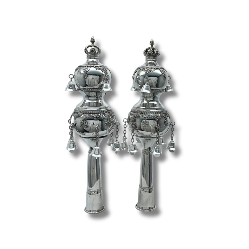 Handcrafted silver Torah finials with intricate decorations and bells