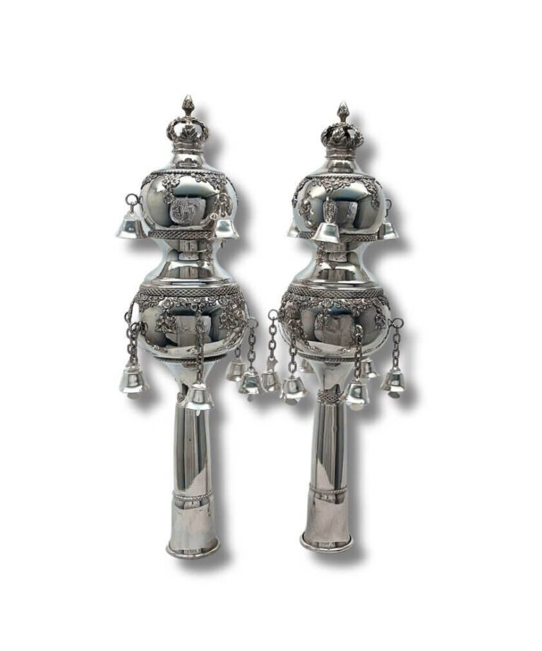 Handcrafted silver Torah finials with intricate decorations and bells