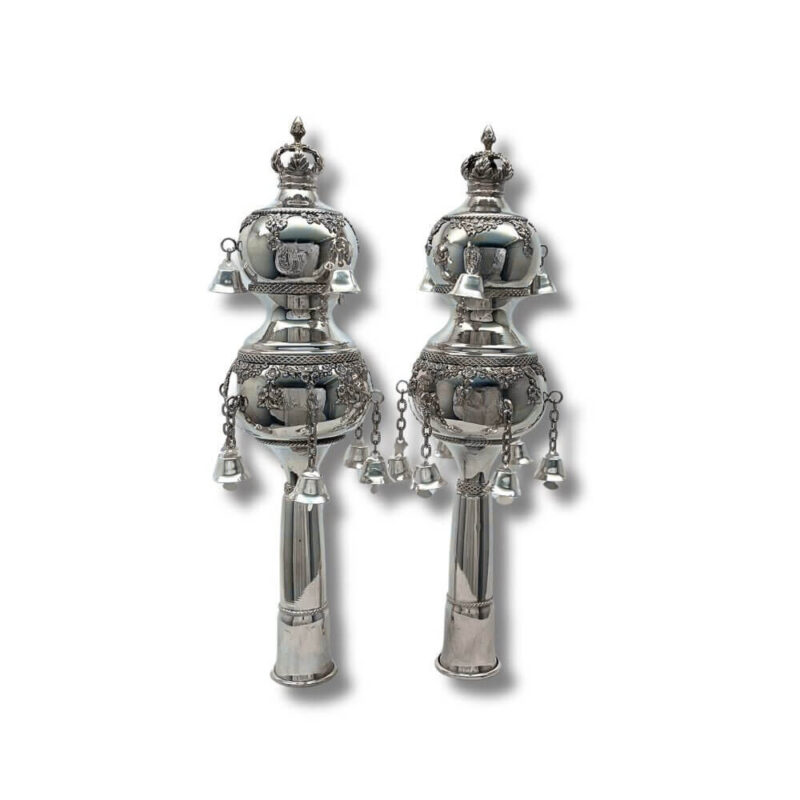 Handcrafted silver Torah finials with intricate decorations and bells