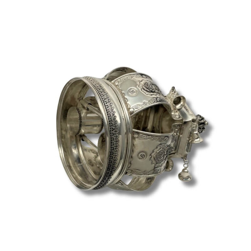 Angled view of the ornate silver Torah Crown with floral motifs and bells