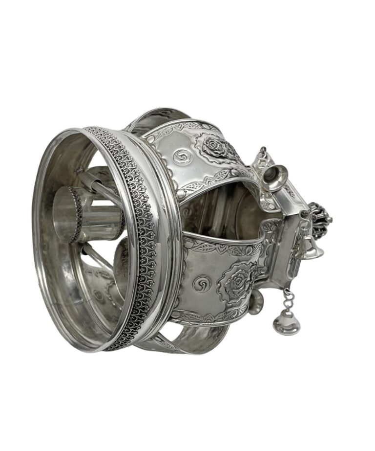 Angled view of the ornate silver Torah Crown with floral motifs and bells