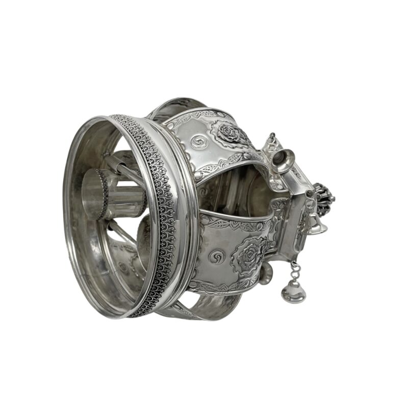 Angled view of the ornate silver Torah Crown with floral motifs and bells