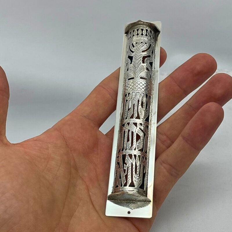 Sterling Silver Mezuzah Case held in hand, showcasing detailed filigree and Hebrew engraving
