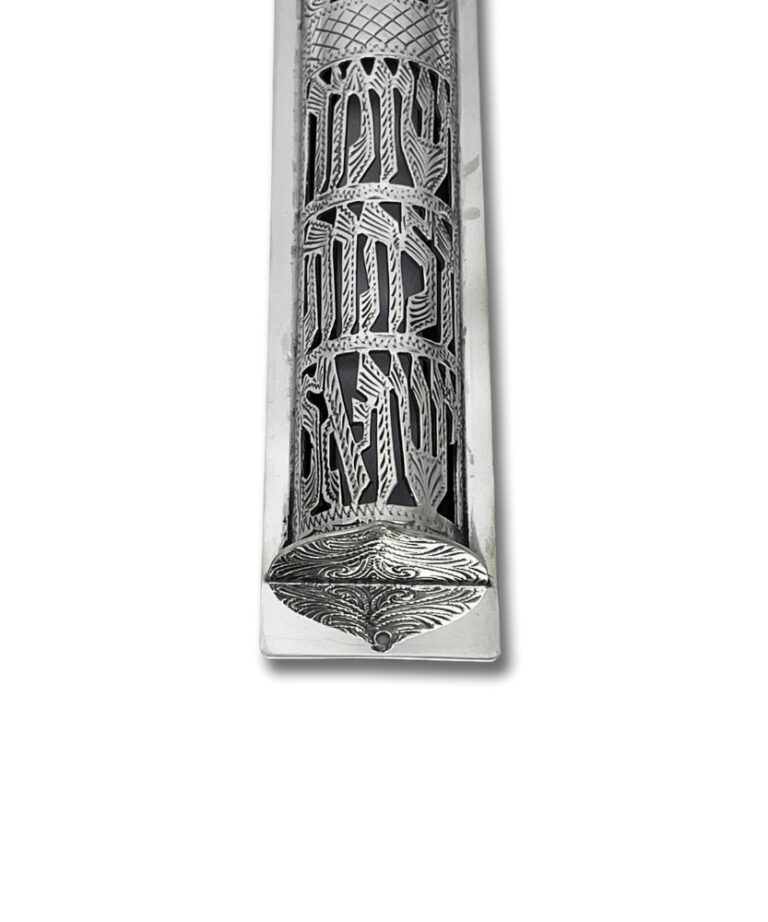 Close-up of engraved Hebrew letters and floral designs on the silver mezuzah
