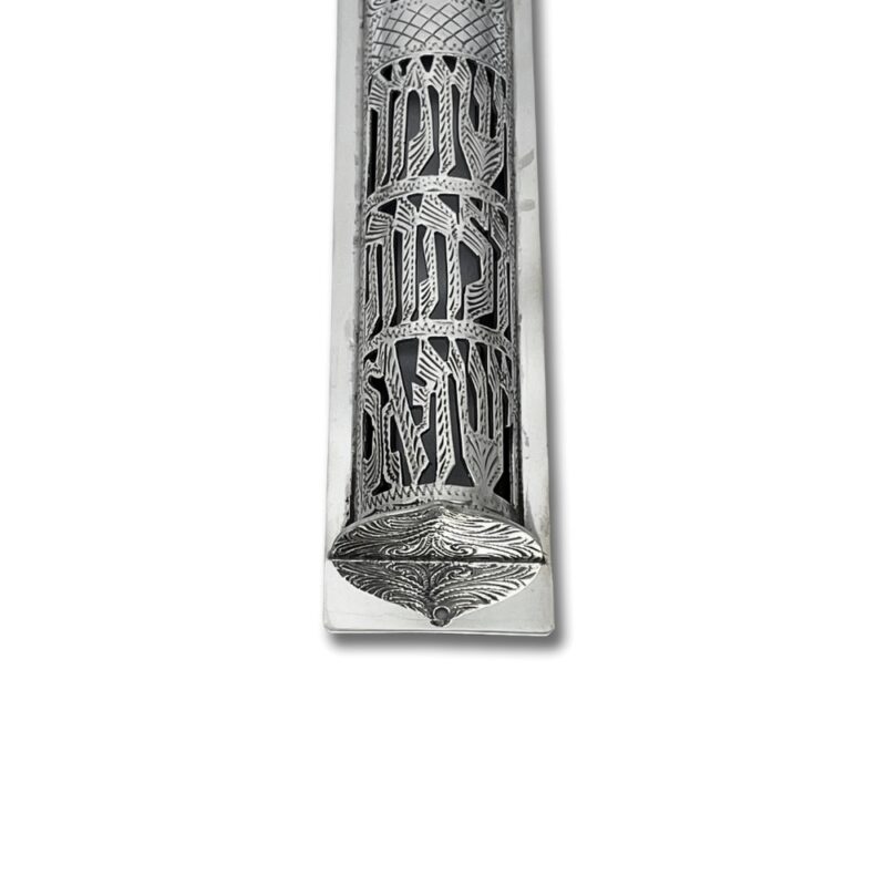 Close-up of engraved Hebrew letters and floral designs on the silver mezuzah