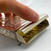 Close-up of a hand lifting the lid of a piano-shaped spice box with golden keys