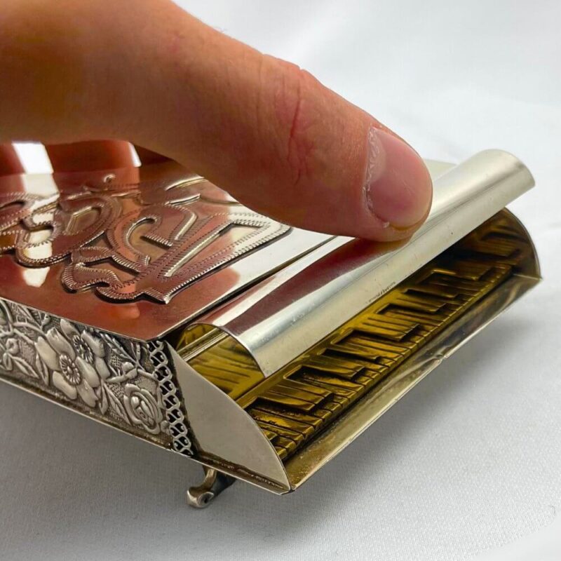 Close-up of a hand lifting the lid of a piano-shaped spice box with golden keys