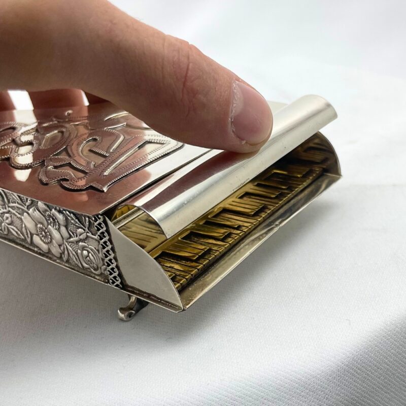 Close-up of a hand lifting the lid of a piano-shaped spice box with golden keys