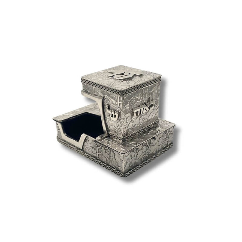 Top-down angle of silver tefillin box with bold “יד” engraving and ornate surface