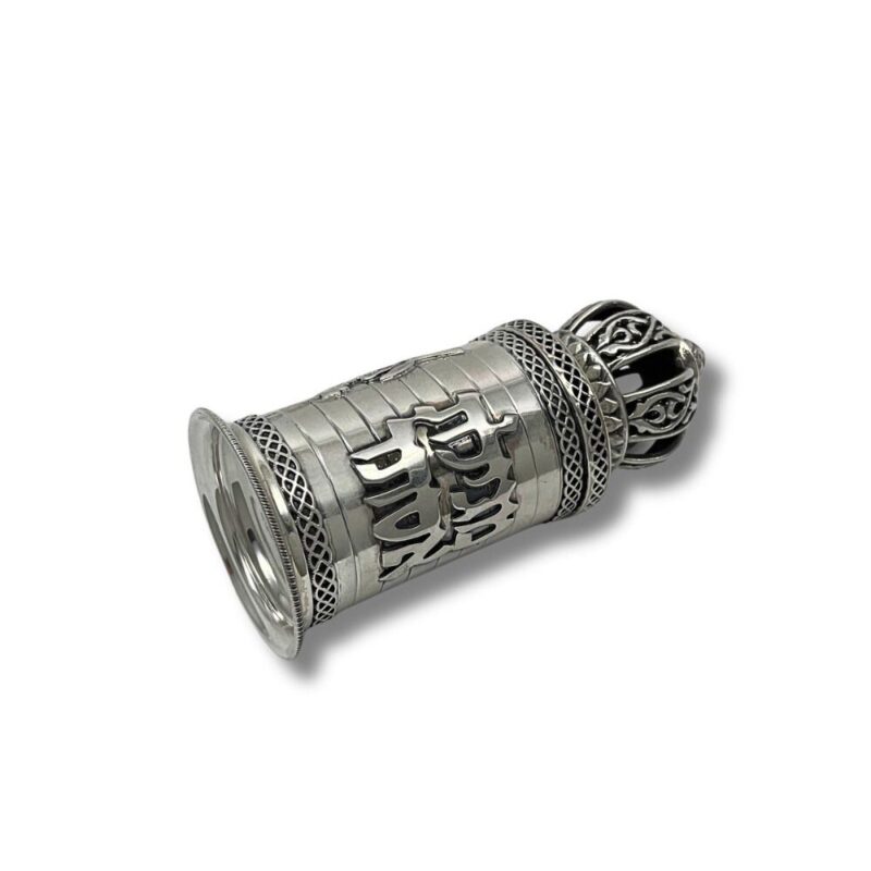 Ornate silver scroll case with black crown-shaped lid lying on its side