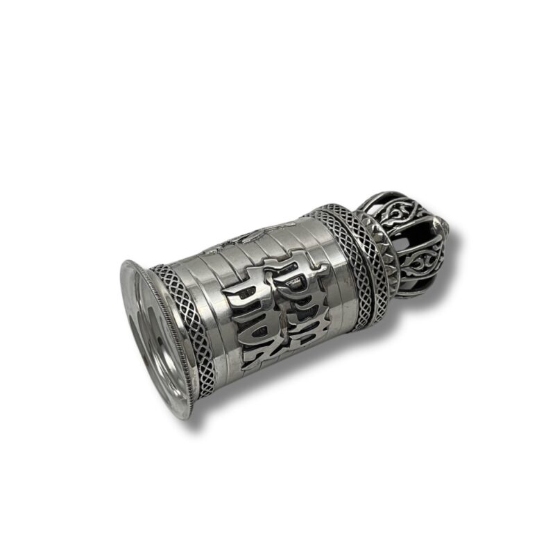 Ornate silver scroll case with black crown-shaped lid lying on its side