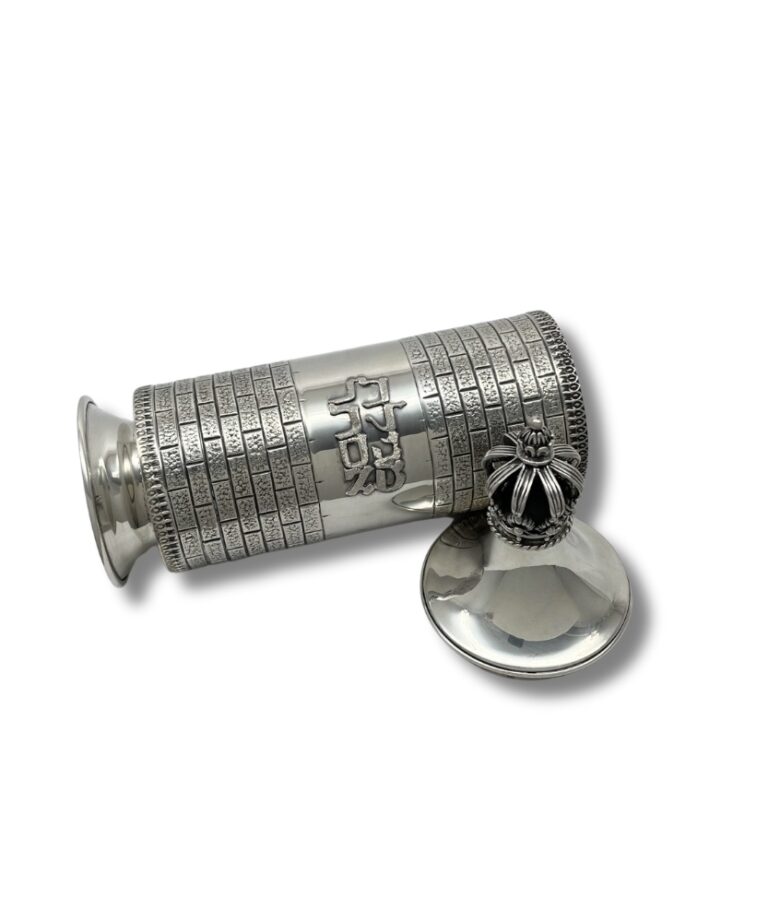 Decorative silver Megillah case lying open with detached crown lid beside it