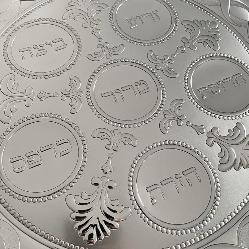 Detailed view of all six engraved Passover food labels on the silver Seder plate