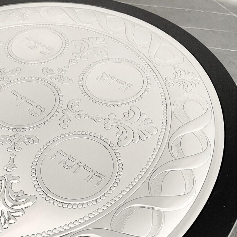 Close-up of the engraved Charoset, Z’roa and Beitzah sections with floral decorations on the Seder plate