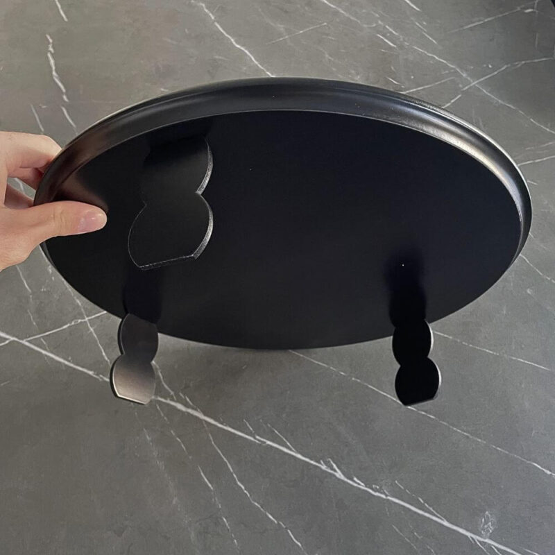 Underside of the Seder plate showing the smooth black wooden base and sturdy legs