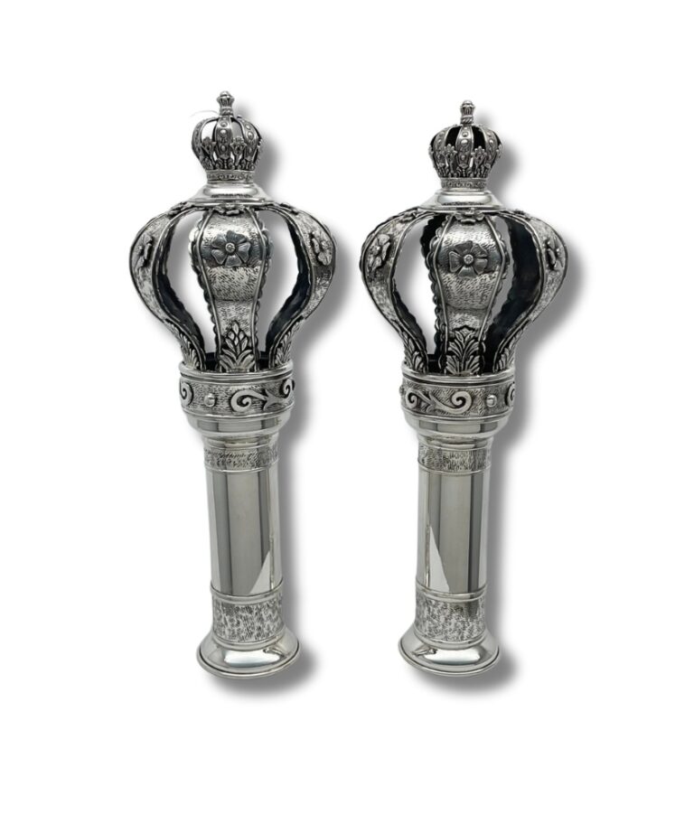 Angled view of 925 sterling silver Torah finials showing floral crowns with open sections and polished stems