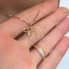 Gold Chai outline necklace displayed in hand with natural light