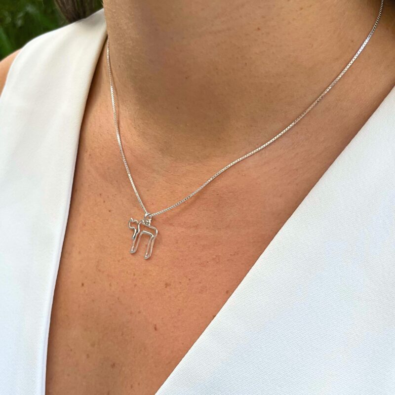 white gold outline Chai pendant worn outdoors with natural lighting